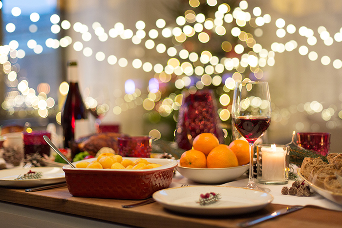 Food and wine on a festive table with Christmas lights in the background.