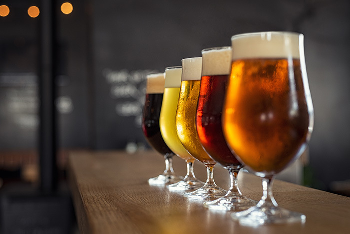 Five types of beer in glasses lined up on a bar.